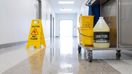 Janitori No.61 floor cleaner on a janitorial cart beside a mop bucket and wet-floor sign in a facility corridor