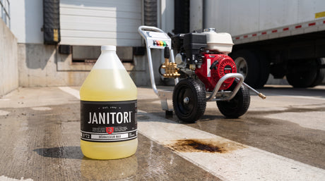 Commercial gas pressure washer with a hose and wand on a clean concrete loading dock, a JANITORI Degreaser MAX No.72 jug beside it